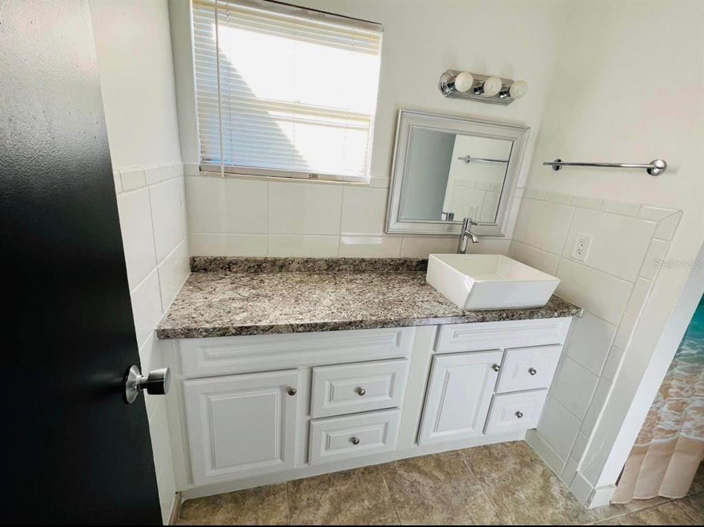 707 Southwest 75th Street, Unit 109 Gainesville, FL 32607 - Photo 11 of 13 a bathroom with a granite countertop sink and a mirror