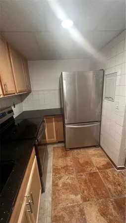 a view of a refrigerator in kitchen and an empty room