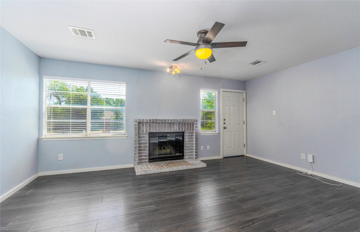 1845 River Crossing Circle, Unit C Austin, TX 78741 - Photo 28 of 28 an empty room with wooden floor a fireplace and a window