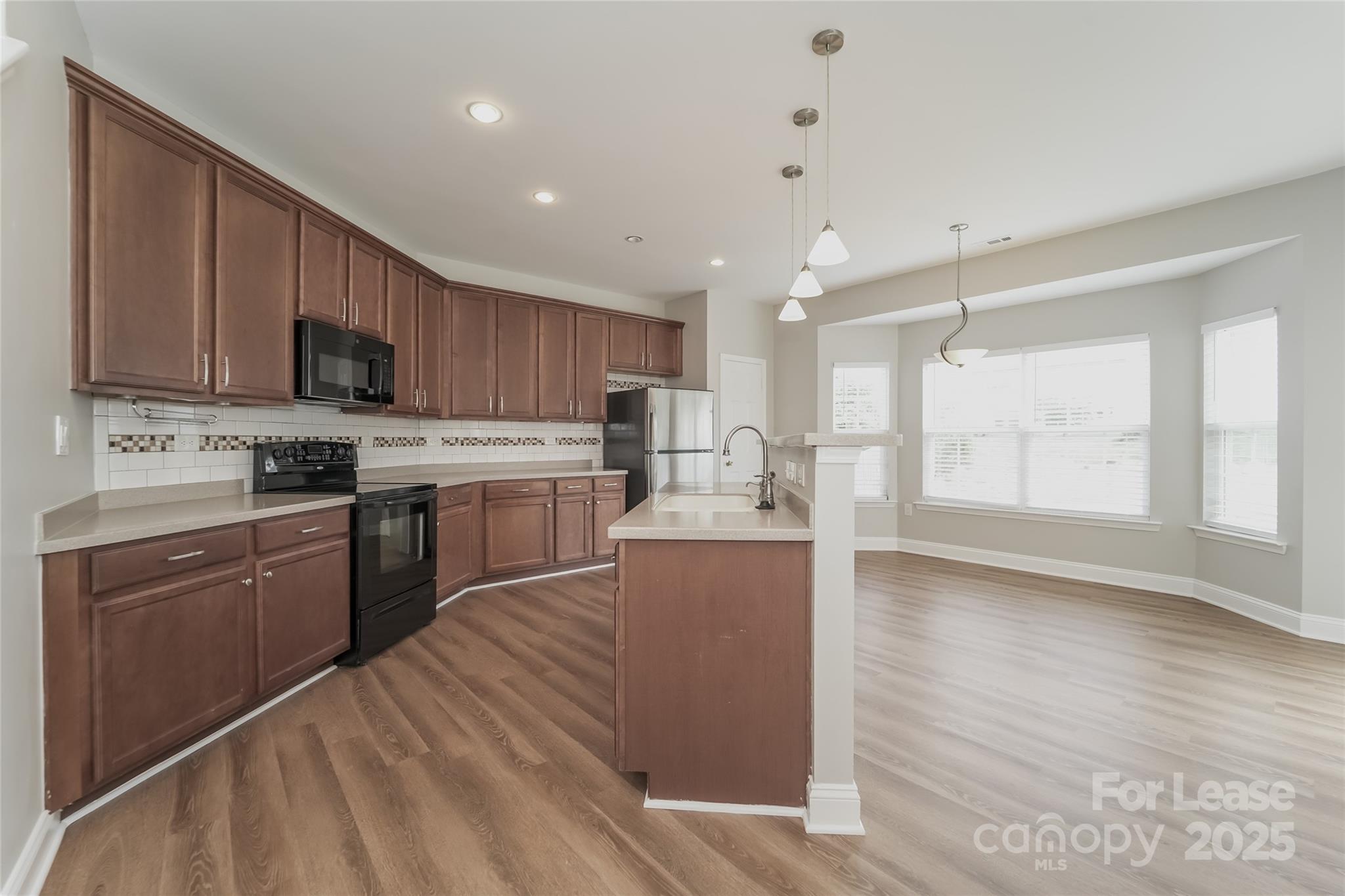 4416 Marys Point Road Monroe, NC 28110 - Photo 8 of 12 a kitchen with stainless steel appliances granite countertop a stove top oven a sink dishwasher and a refrigerator with wooden floor