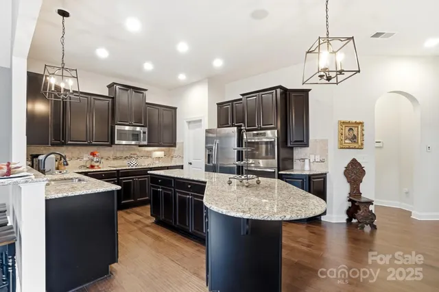 a kitchen with stainless steel appliances granite countertop a stove refrigerator and a view of living room