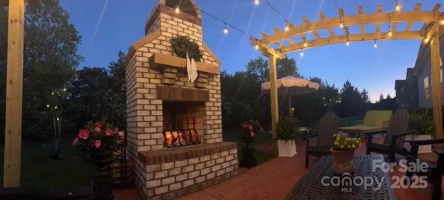 a view of a patio with a table and chairs under an umbrella with a fire pit and barbeque grill