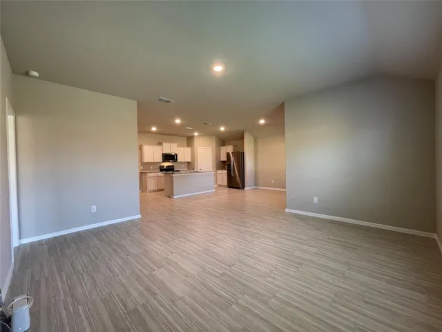 a view of a big room with wooden floor and a kitchen