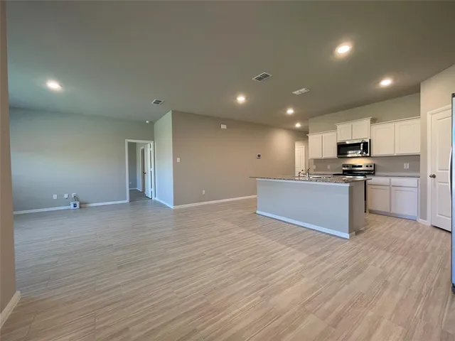 a view of kitchen with kitchen island wooden floor and stainless steel appliances