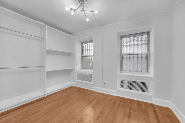 an empty room with wooden floor cabinet and windows