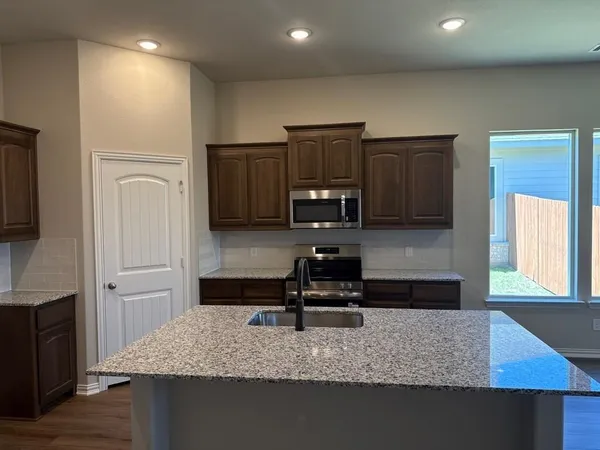 a kitchen with kitchen island granite countertop a stove a sink and a refrigerator