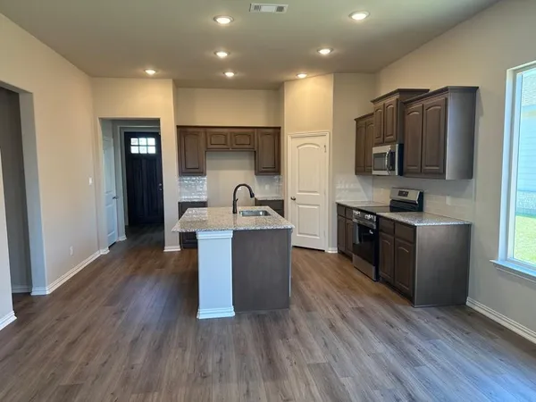 a kitchen with kitchen island stainless steel appliances a sink cabinets and wooden floor