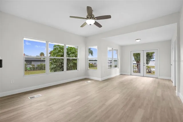 a view of empty room with wooden floor and fan