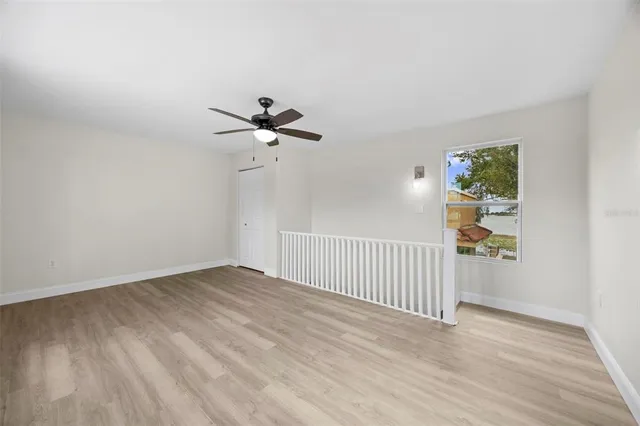 a view of empty room with wooden floor and fan