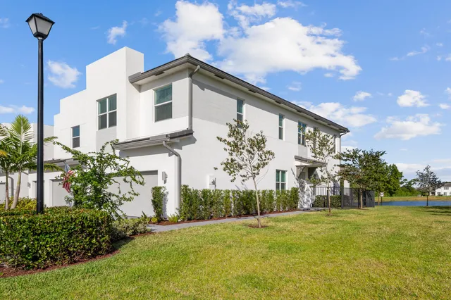 a view of a white house with a big yard and potted plants