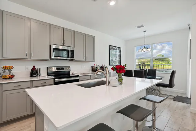 a kitchen with sink a microwave and dining table with chairs