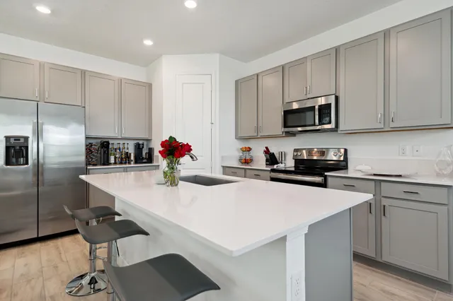 a kitchen with stainless steel appliances a stove a sink a microwave a refrigerator and cabinets