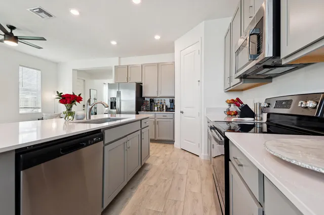 a kitchen with stainless steel appliances a sink dishwasher stove refrigerator and cabinets
