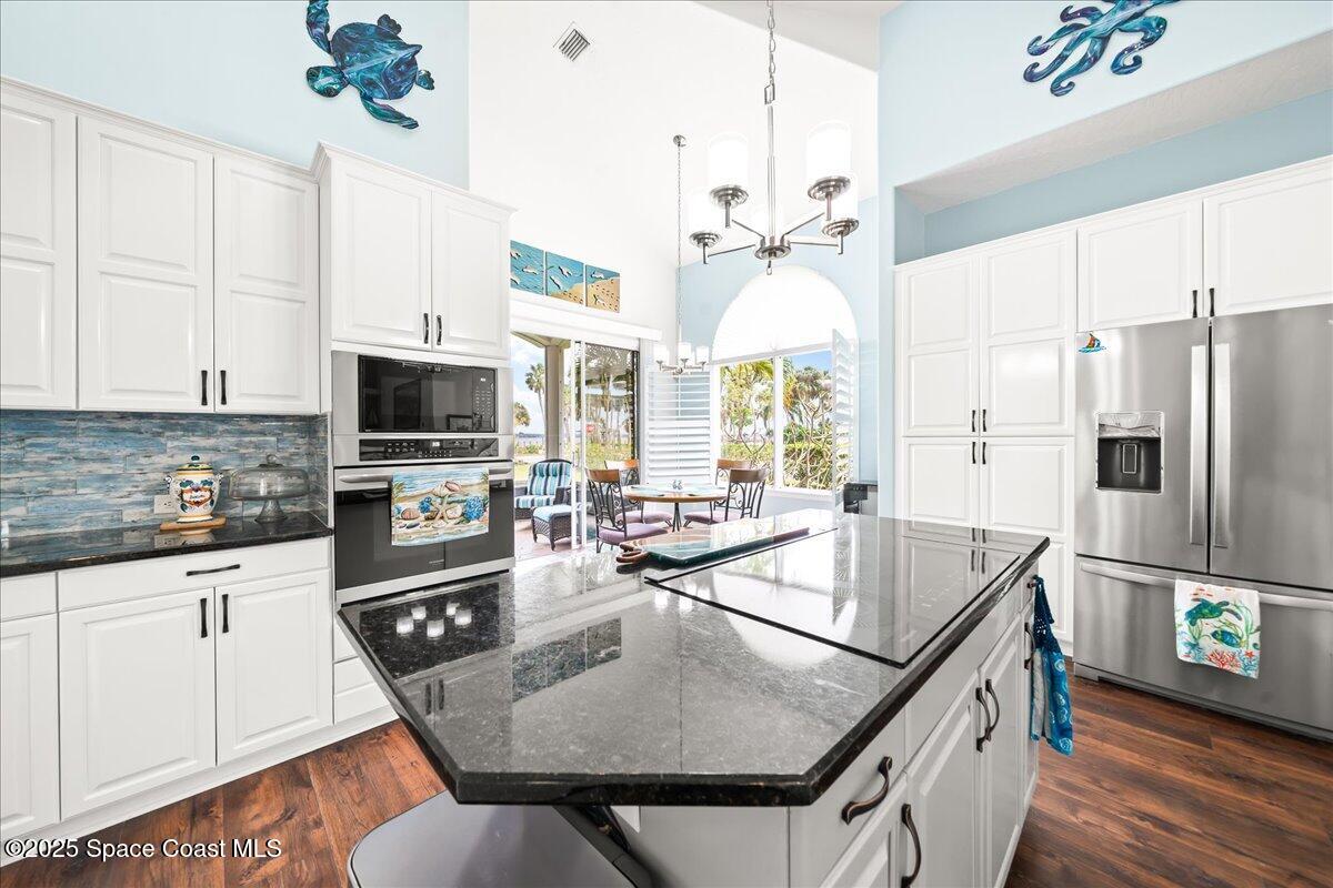 2089 Rockledge Drive Rockledge, FL 32955 - Photo 16 of 60 a kitchen with stainless steel appliances granite countertop a sink dishwasher a refrigerator a microwave oven with a dining table and chairs with wooden floor