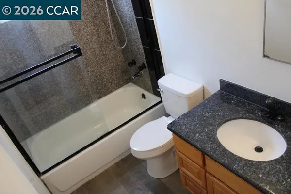 a bathroom with a granite countertop sink mirror vanity and toilet