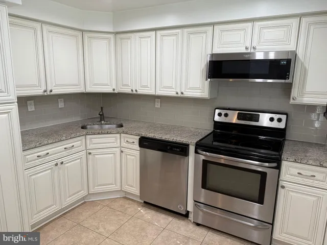 a kitchen with white cabinets and black appliances
