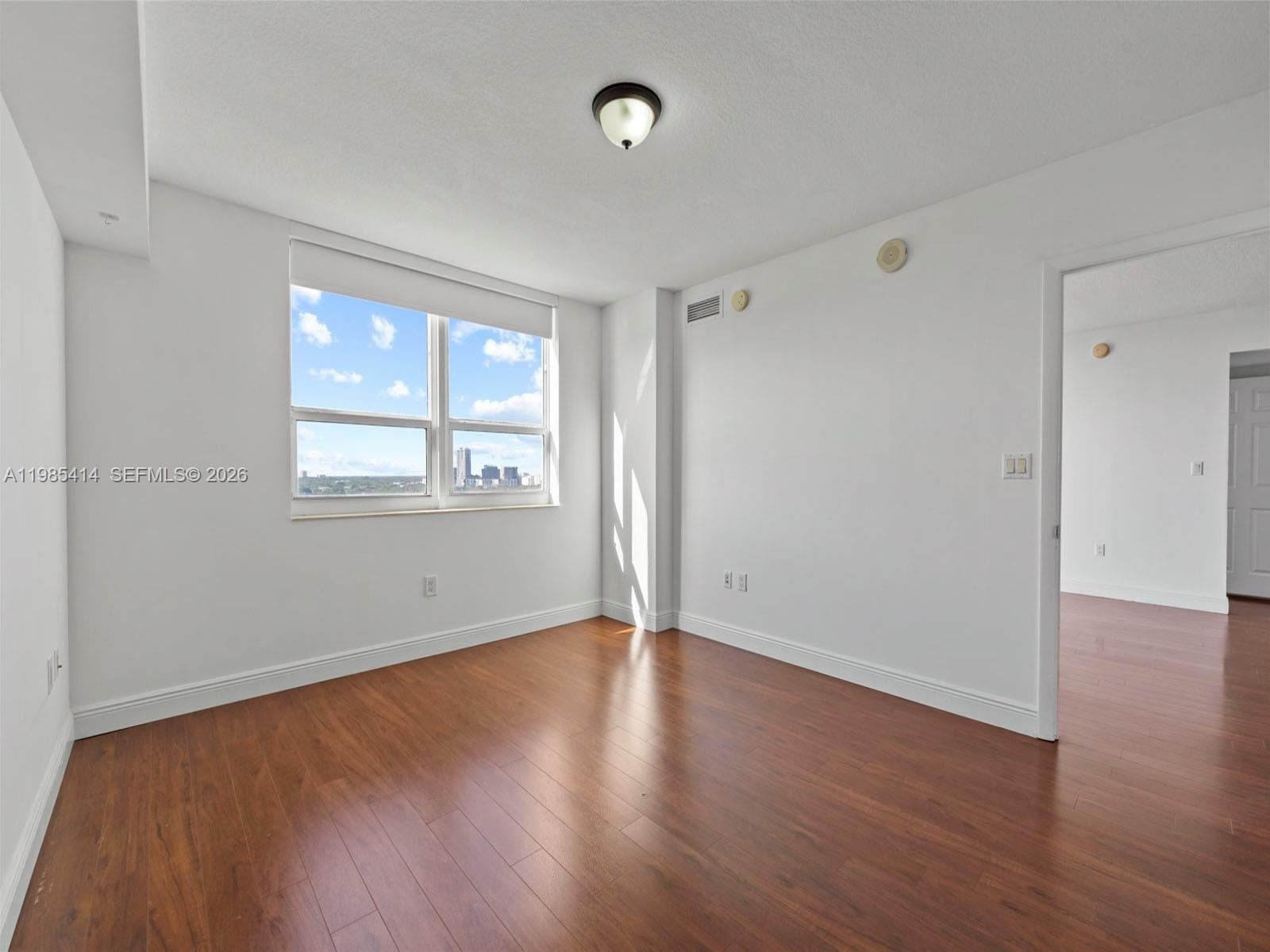 3232 Southwest 22nd Terrace, Unit 1609 Miami, FL 33145 - Photo 18 of 37 a view of an empty room with wooden floor and a window