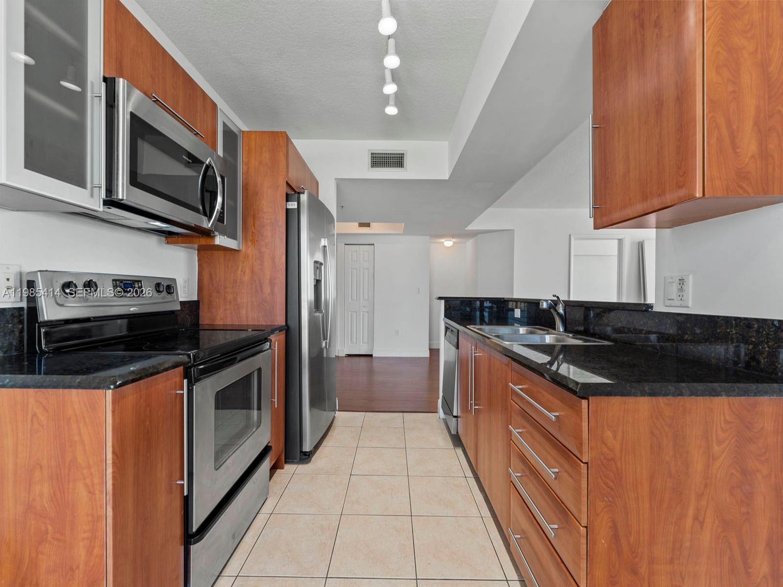3232 Southwest 22nd Terrace, Unit 1609 Miami, FL 33145 - Photo 6 of 37 a kitchen with stainless steel appliances granite countertop a stove a sink and a microwave
