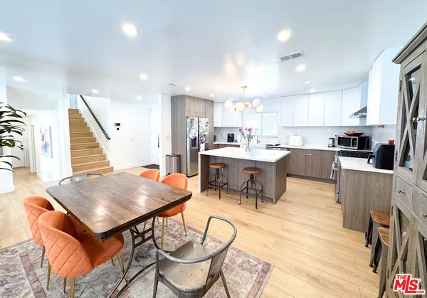a room with stainless steel appliances kitchen island a table and chairs in it