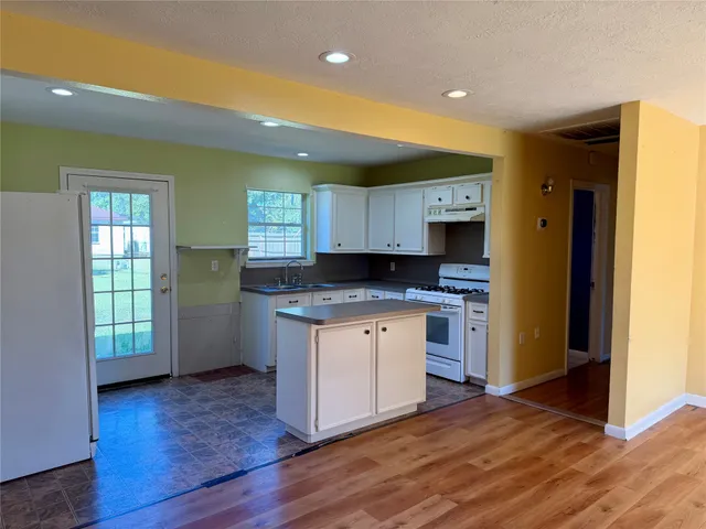 a kitchen with granite countertop wooden floors and white stainless steel appliances