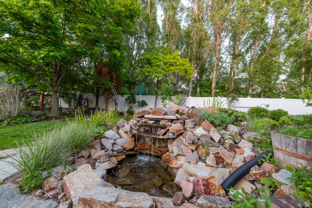6208 West Bull River Road Highland, UT 84003 - Photo 63 of 90 Expansive backyard featuring a rock water feature, manicured lawn, mature trees, and a white privacy fence