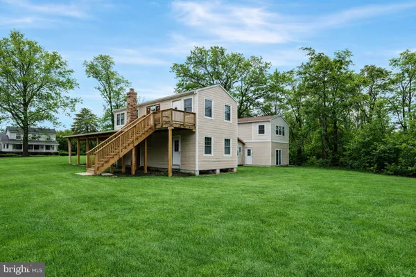 a white house that has a big yard and a big trees with wooden fence