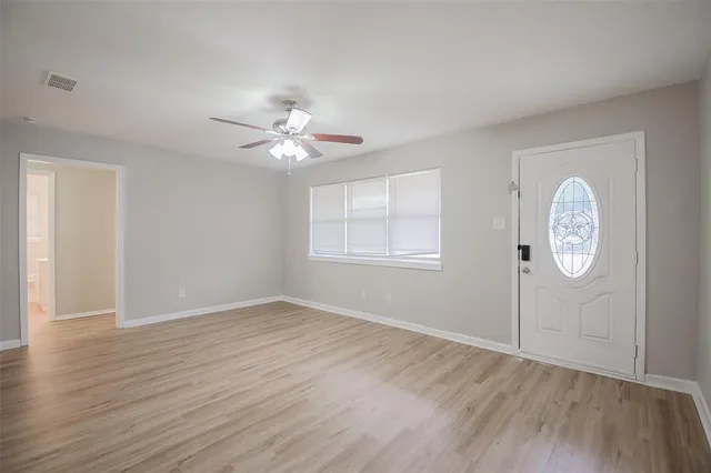 an empty room with wooden floor and window