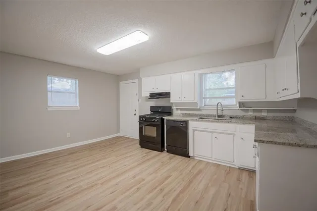 a kitchen with granite countertop a stove top oven sink and cabinets