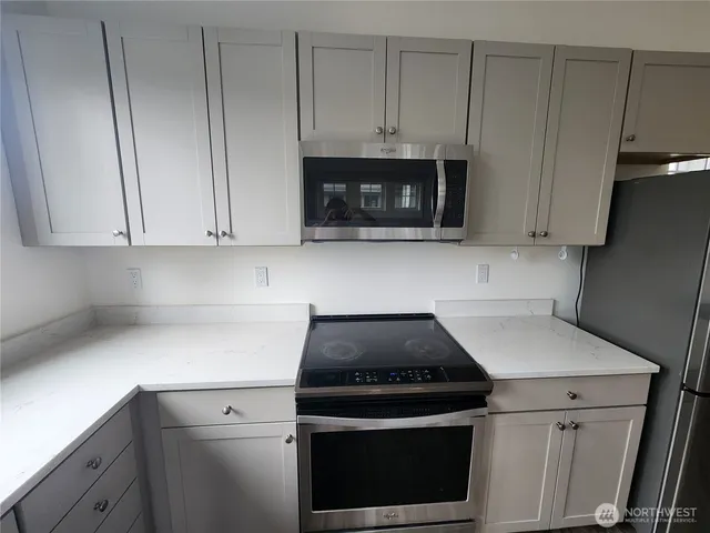 a kitchen with white cabinets and black appliances