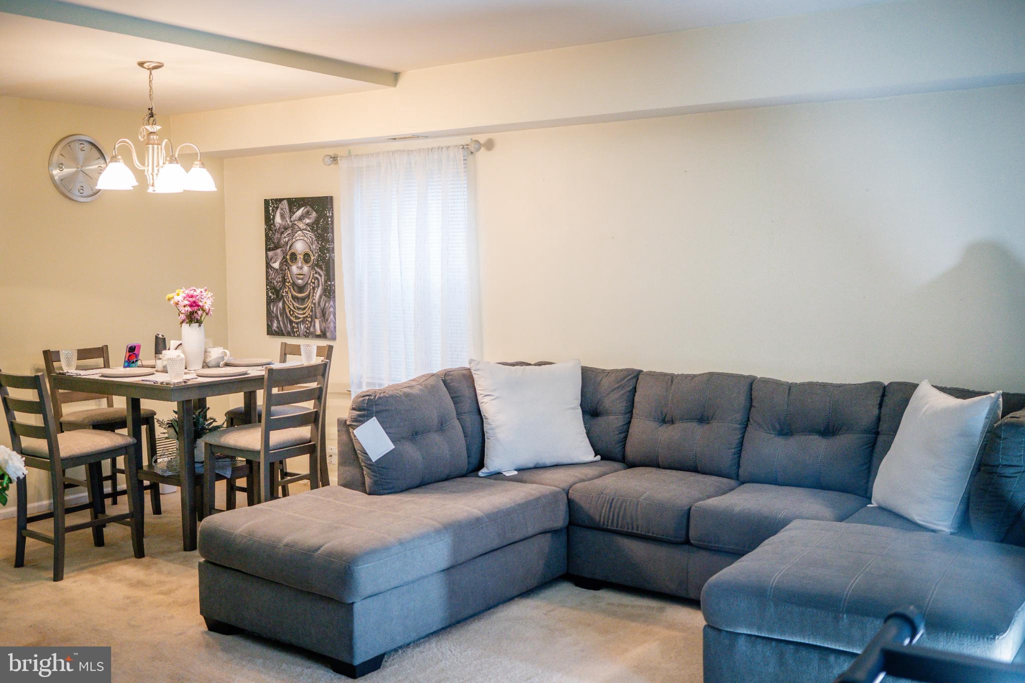 2089 Welsh Road, Unit F1 Philadelphia, PA 19115 - Photo 10 of 27 a living room with furniture a dining table and a chandelier