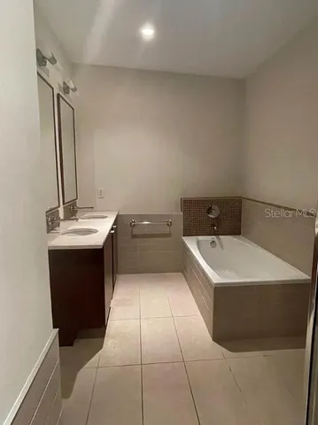 a bathroom with a bathtub sink vanity and mirror