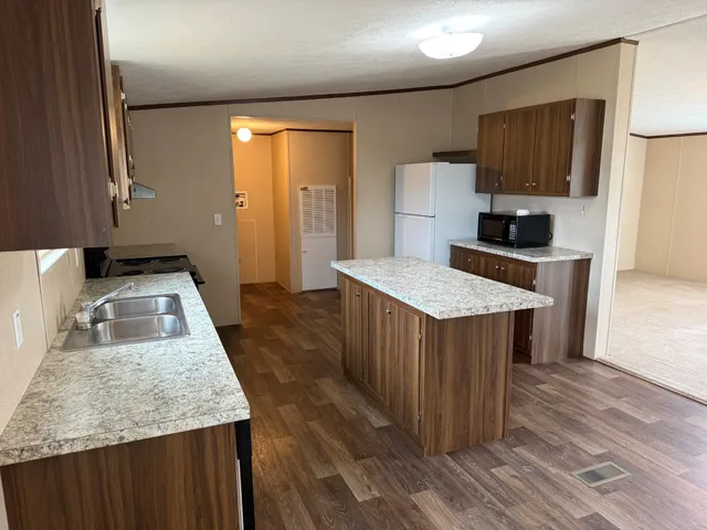 a kitchen with kitchen island granite countertop wooden cabinets a sink and a stove