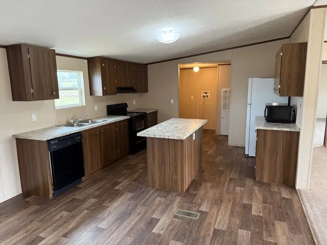 a large kitchen with stainless steel appliances granite countertop a stove a sink dishwasher and a refrigerator with wooden floor