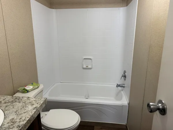 a bathroom with a granite countertop toilet and a bathtub