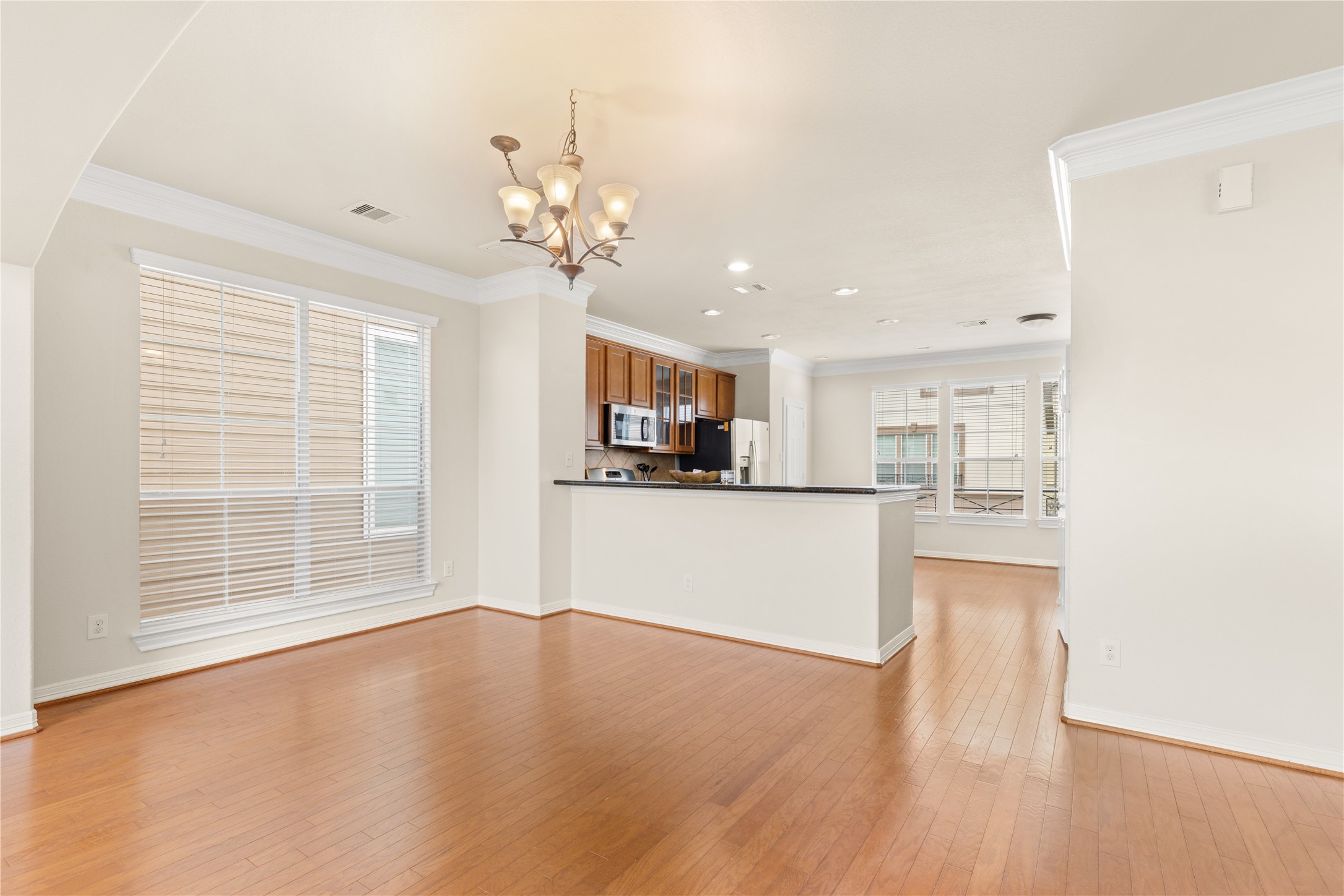3334 Clearview Villa Way Houston, TX 77025 - Photo 8 of 35 This photo showcases a bright, open-concept living space with hardwood floors, a modern kitchen featuring stainless steel appliances, and large windows for ample natural light.