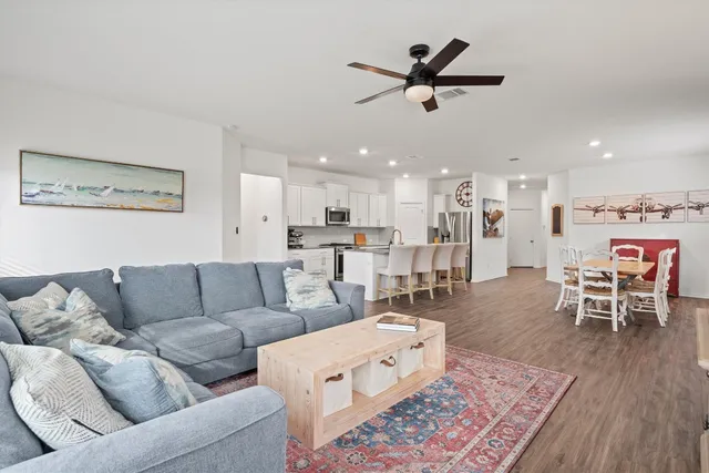 a living room with furniture kitchen view and a wooden floor