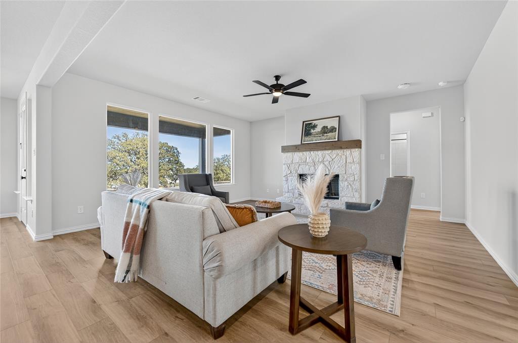 400 Hayden Faith Court Springtown, TX 76082 - Photo 18 of 35 Living area featuring a stone fireplace, light wood finished floors, and a ceiling fan
