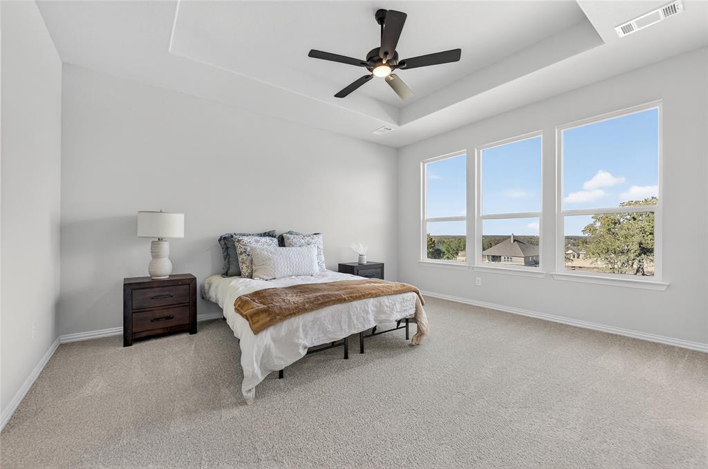 400 Hayden Faith Court Springtown, TX 76082 - Photo 21 of 35 a spacious bedroom with a bed windows and a chandelier