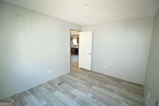 a view of an empty room with wooden floor and closet