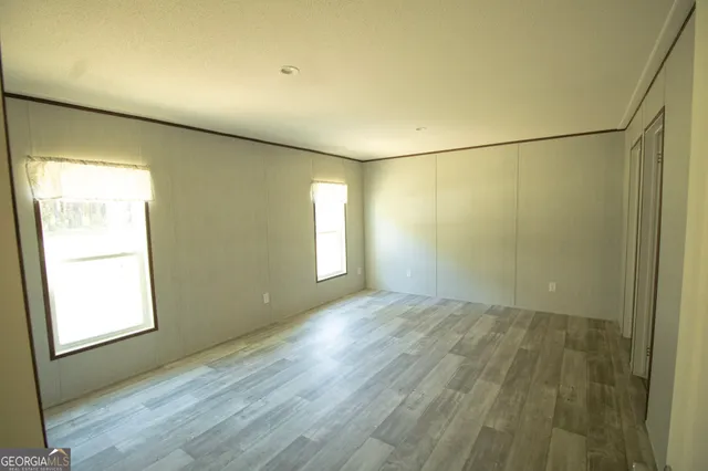 an empty room with wooden floor and windows