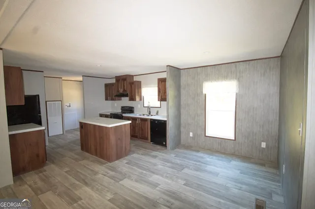 a large kitchen with kitchen island granite countertop a refrigerator sink and cabinets