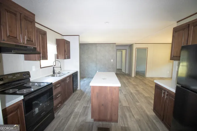 a kitchen with stainless steel appliances granite countertop a stove a sink dishwasher and a refrigerator with wooden floor