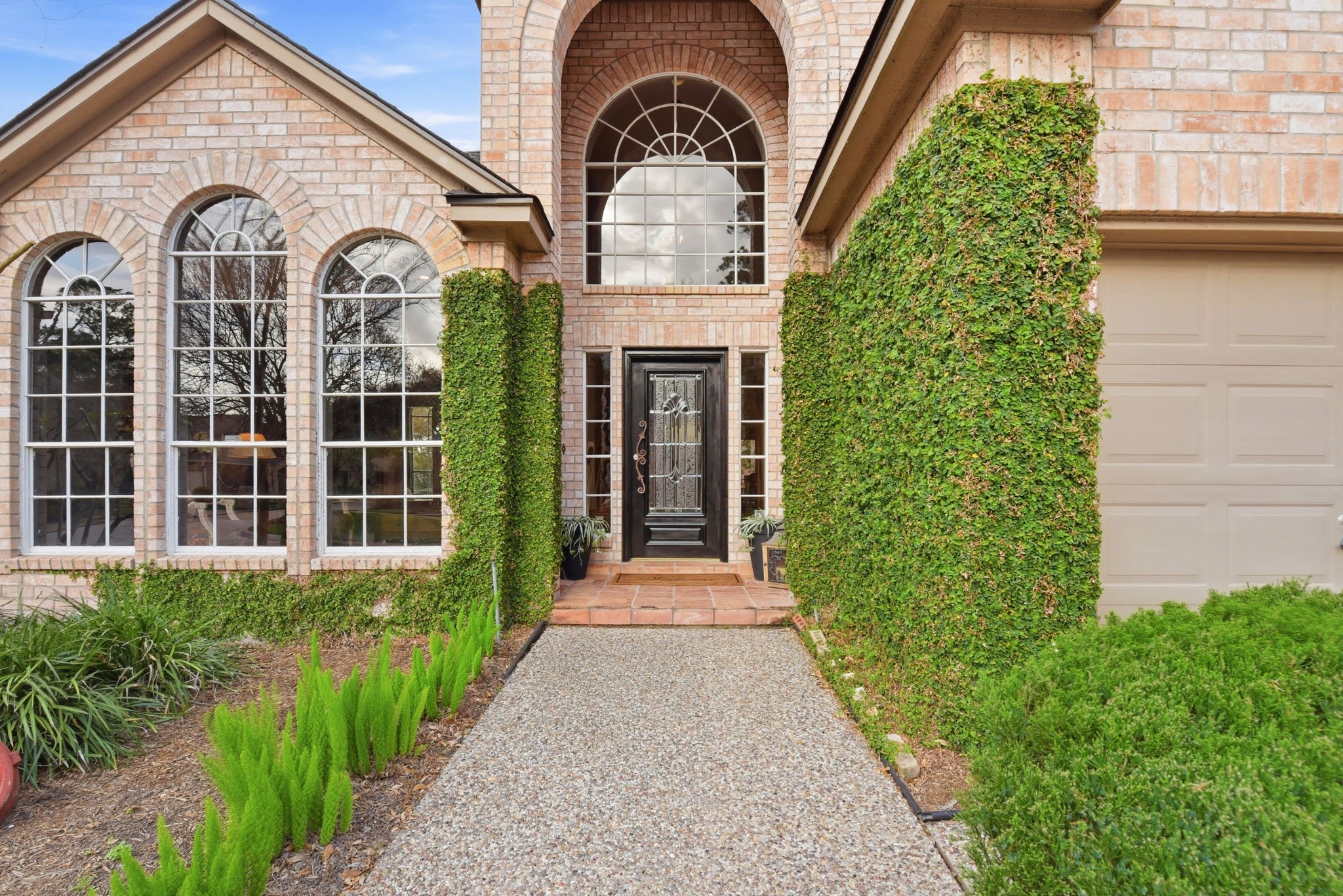 16322 Cranwood Drive Spring, TX 77379 - Photo 3 of 42 Discover the charm of this home's entrance, featuring a stunning leaded glass door, elegant arched windows, and a welcoming pebblestone walkway.