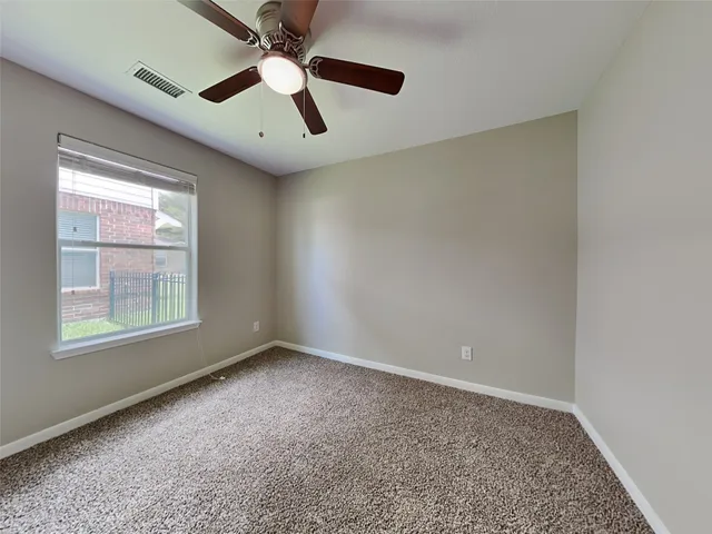 an empty room with chandelier fan and windows