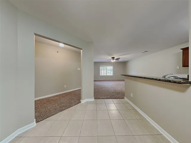 a view of an empty room and a kitchen