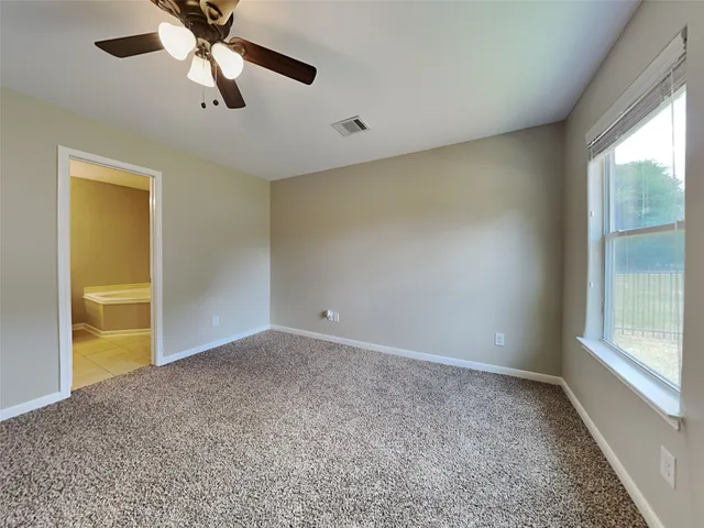 an empty room with chandelier fan and windows