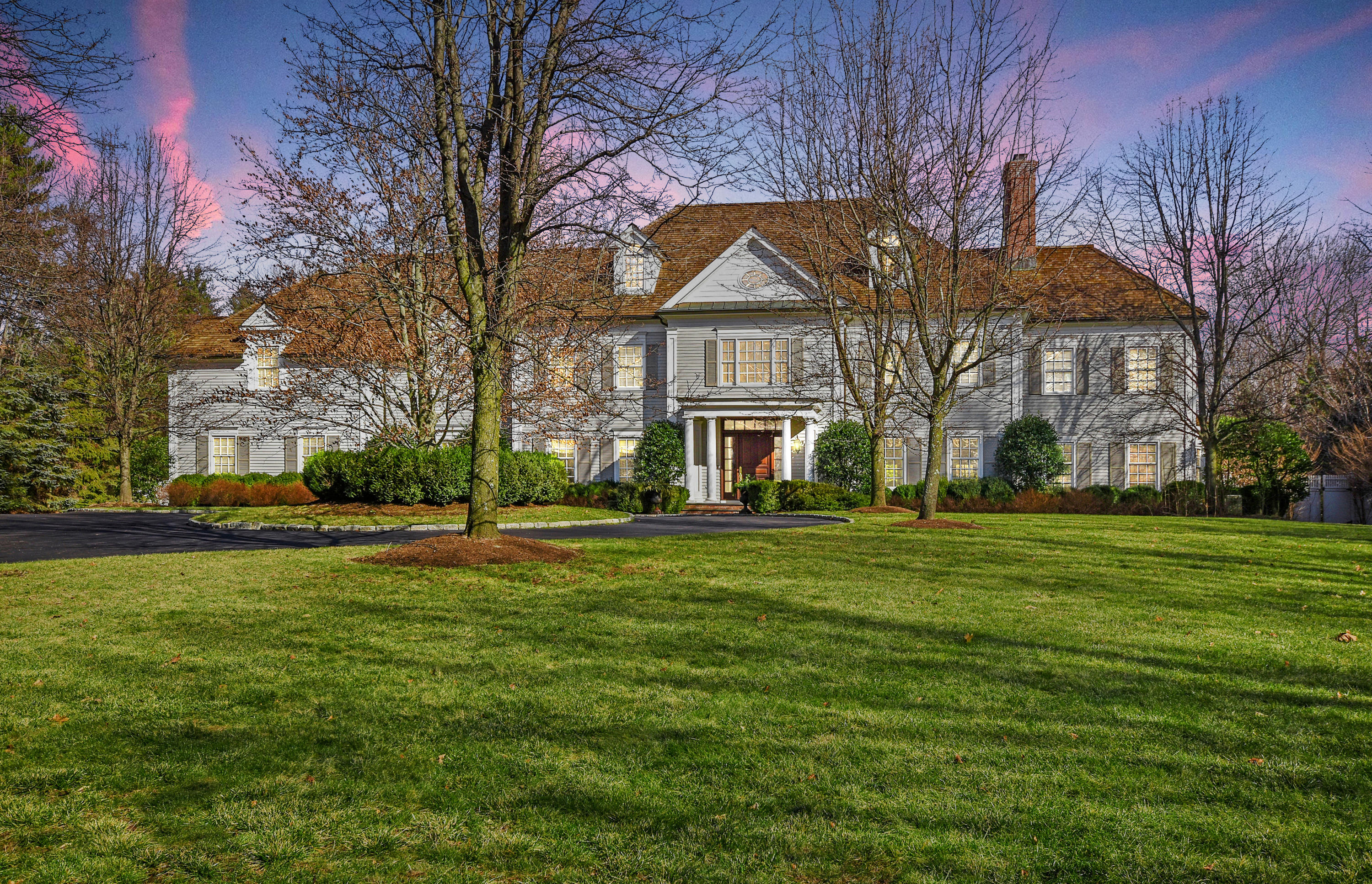 a view of a big house with a big yard and large trees