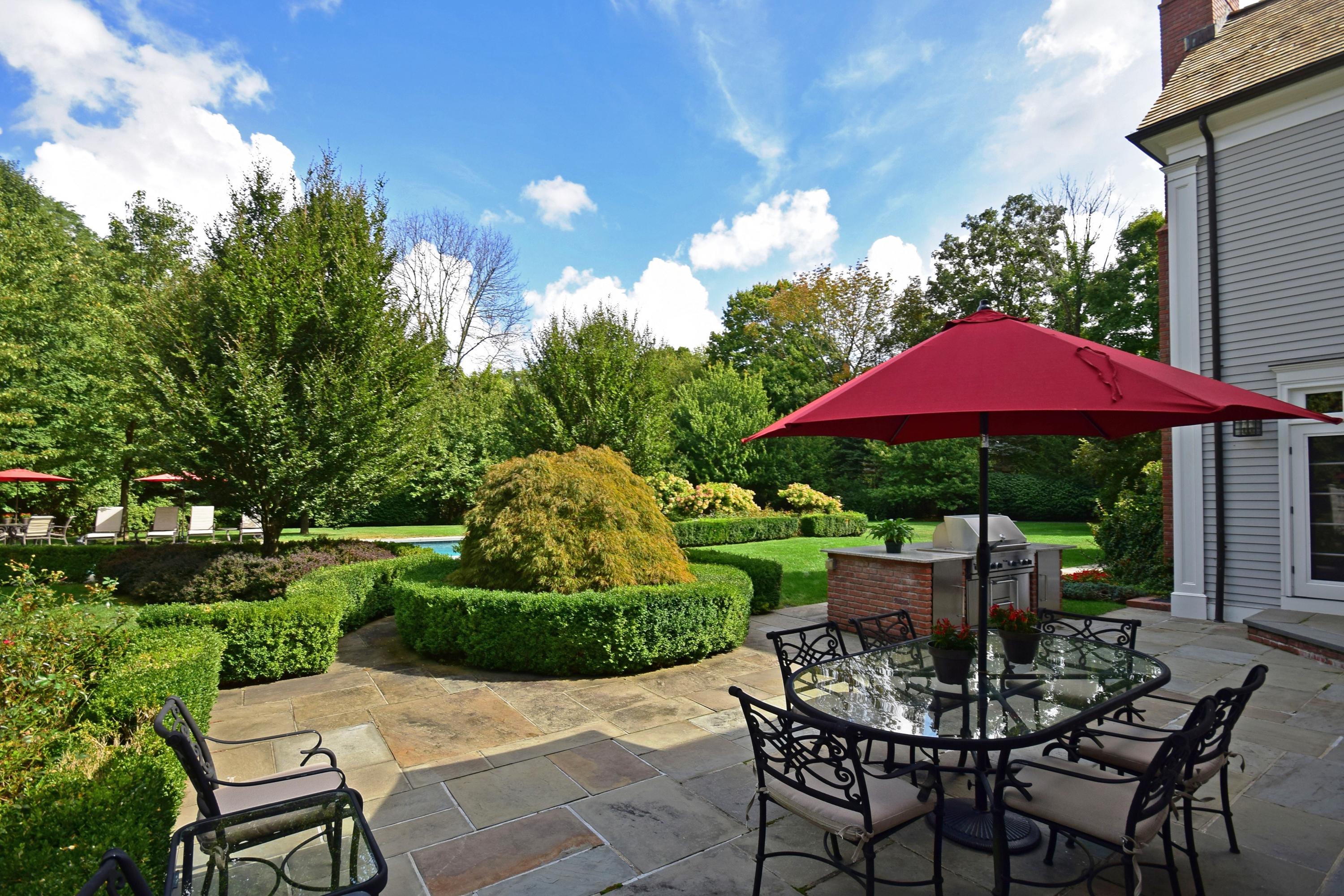 1325 Smith Ridge Road New Canaan, CT 06840 - Photo 23 of 28 a patio with a table and chairs under an umbrella