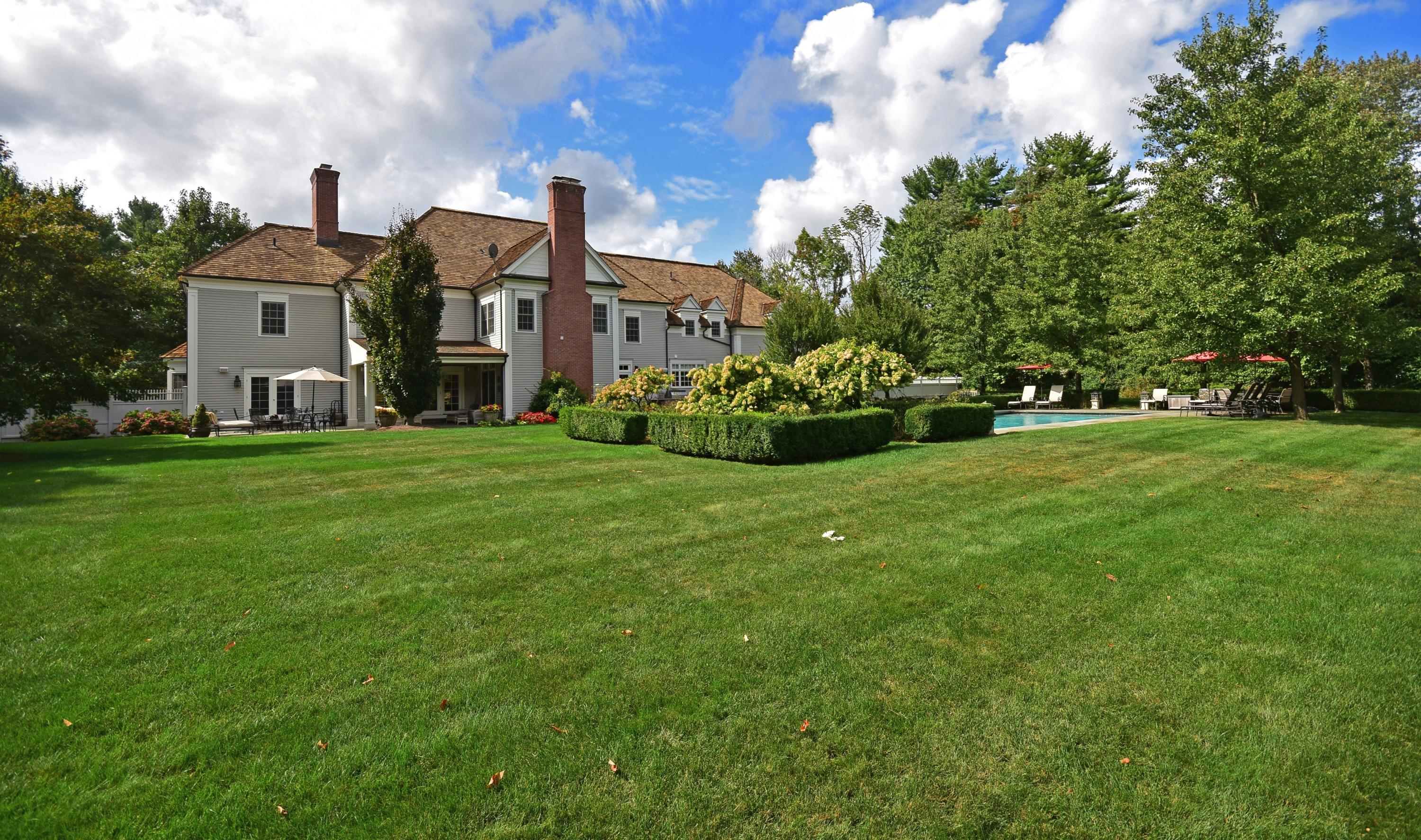1325 Smith Ridge Road New Canaan, CT 06840 - Photo 24 of 28 a view of a white house in front of a big yard with plants and large trees