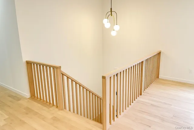 a view of a hallway with wooden floor and chandelier